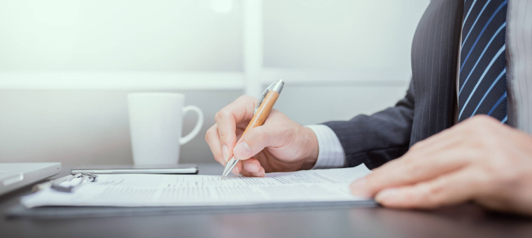 Photo of a Man Writing on Paper