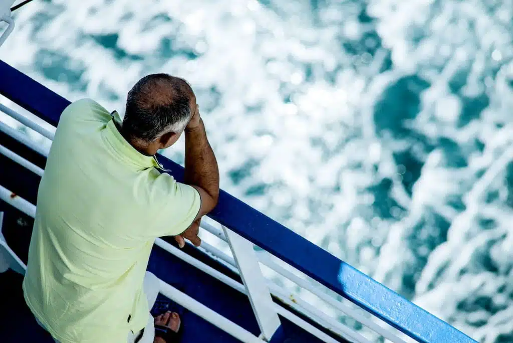 Person Looking Over A Railing In To The Water